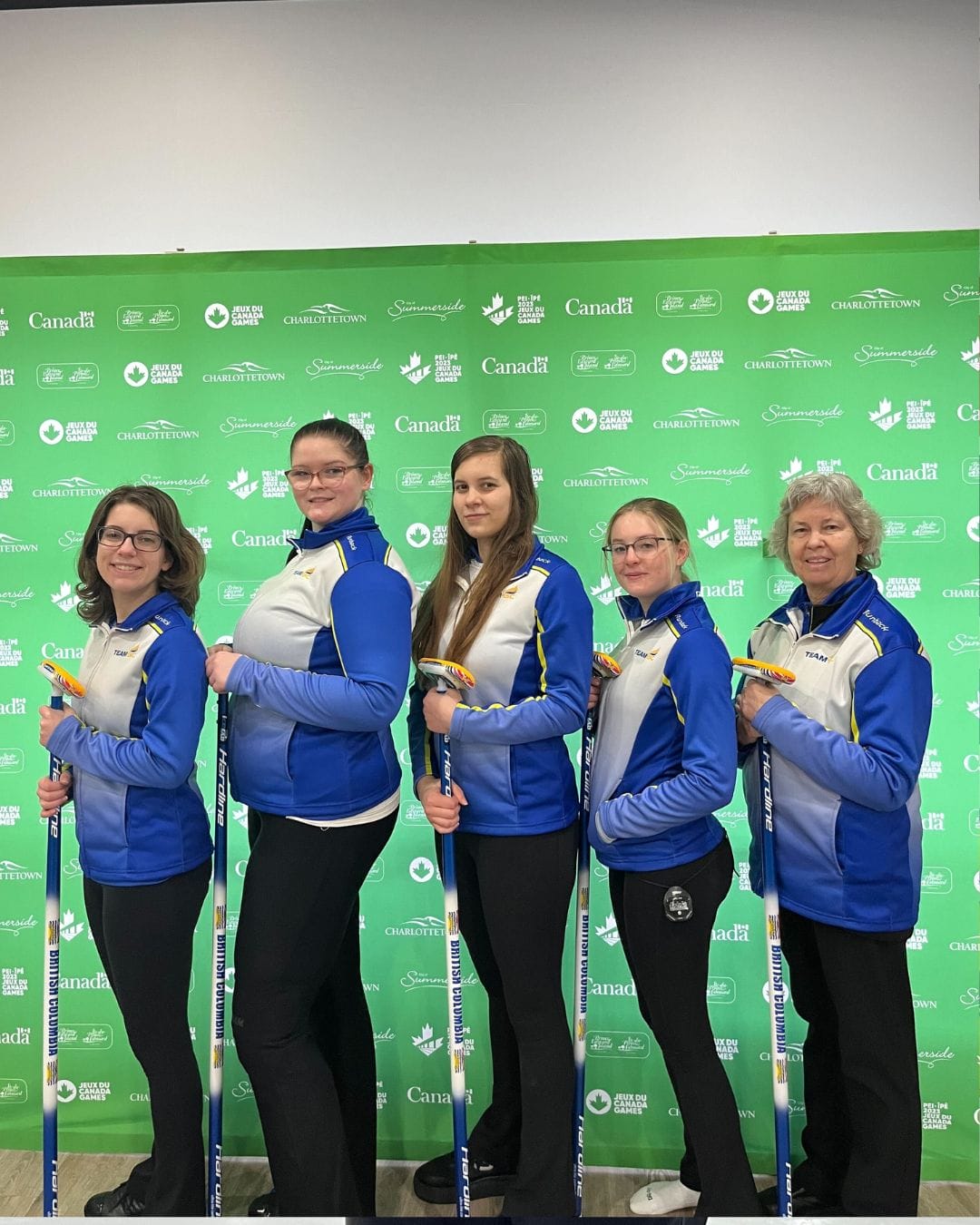 Women's curling team poses with brooms at 2023 Canada Winter Games